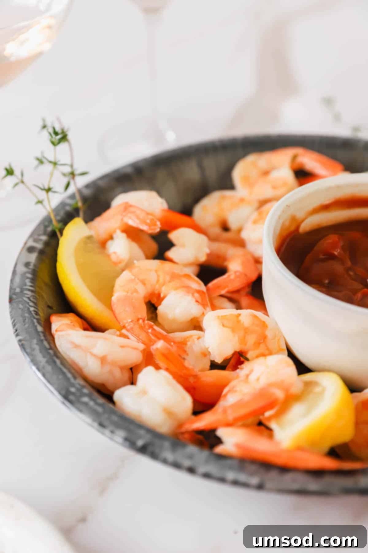 A elegant side view of a platter showcasing perfectly arranged cocktail shrimp, with a small dish of cocktail sauce nestled among them, ready to serve.