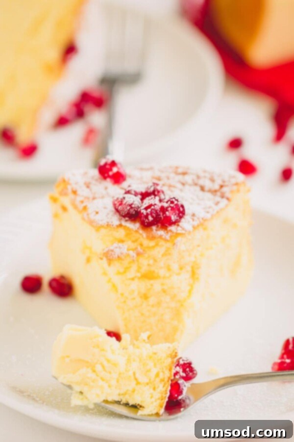 Effortless 3-Ingredient Souffle Cheesecake 2 A slice of incredibly light and fluffy soufflé cheesecake, garnished with fresh berries and powdered sugar, on a white plate.