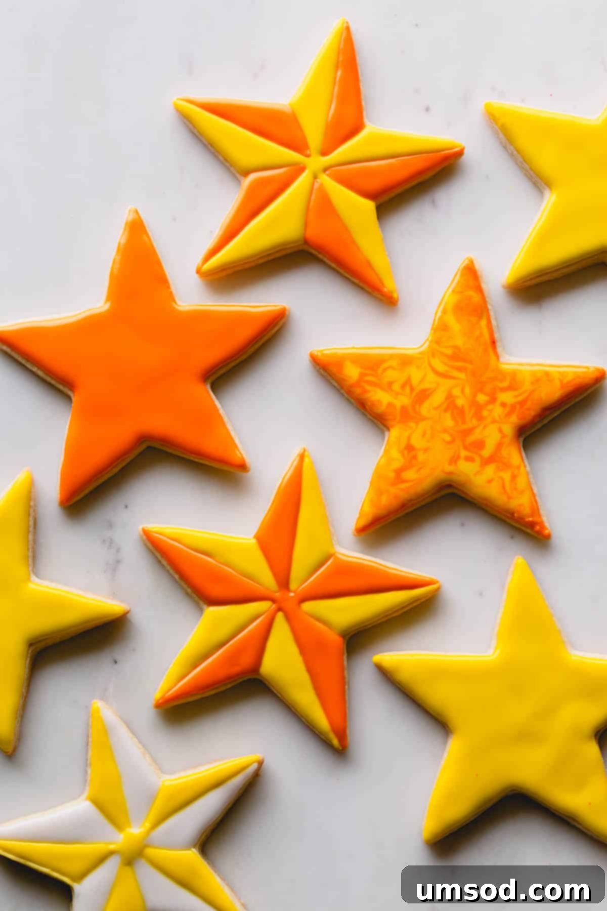 Cheerful yellow and orange star sugar cookies, beautifully decorated on a pristine white background.