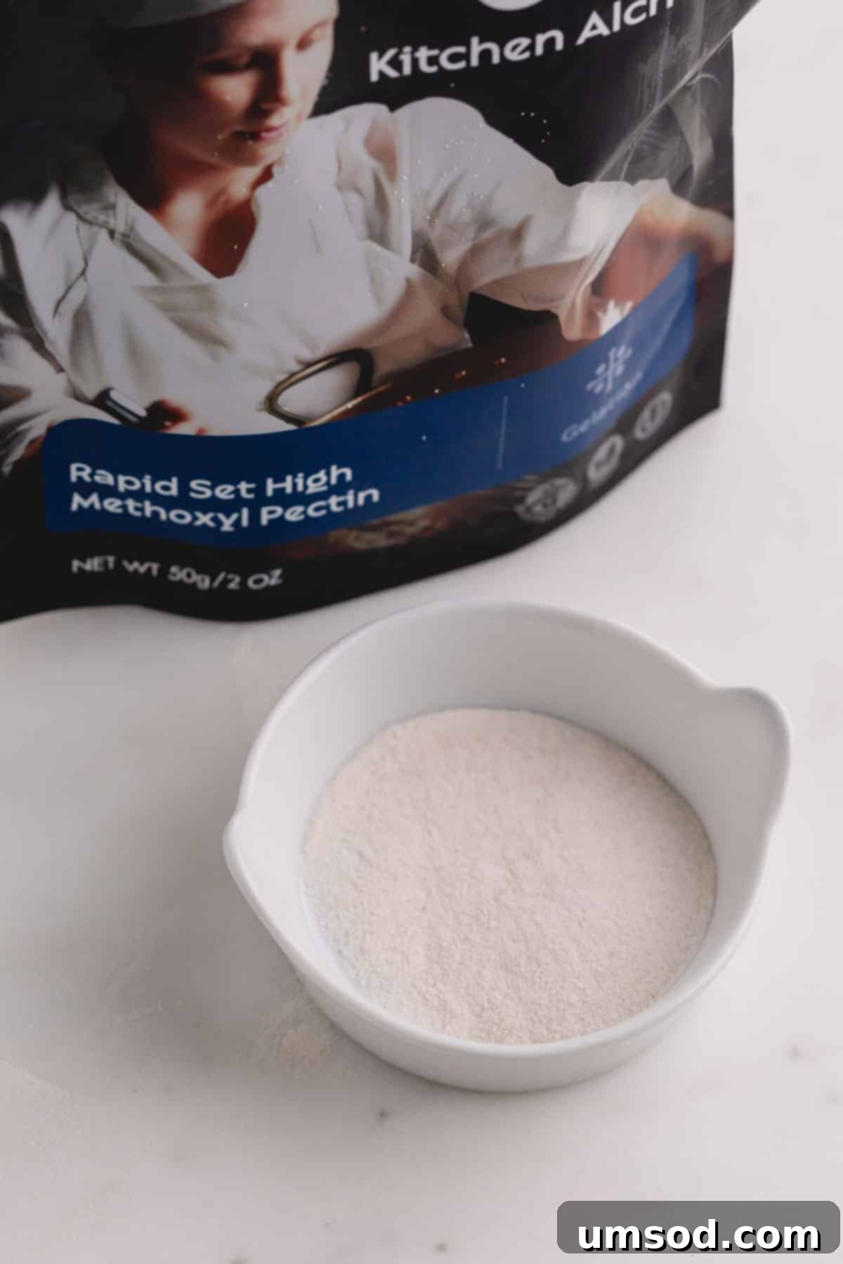 Demystifying Thickening Agents 7 A small white ceramic dish is filled with fine white pectin powder, with its original commercial packaging visible in the soft-focus background.