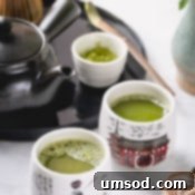 Matcha 101 7 Close-up of a bamboo whisk (chasen) carefully preparing vibrant green matcha tea in a ceramic bowl, with a rich, frothy texture forming.