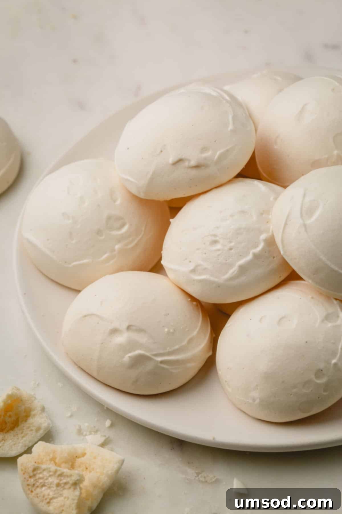 Perfectly baked vegan meringue bites arranged delicately on a plate.