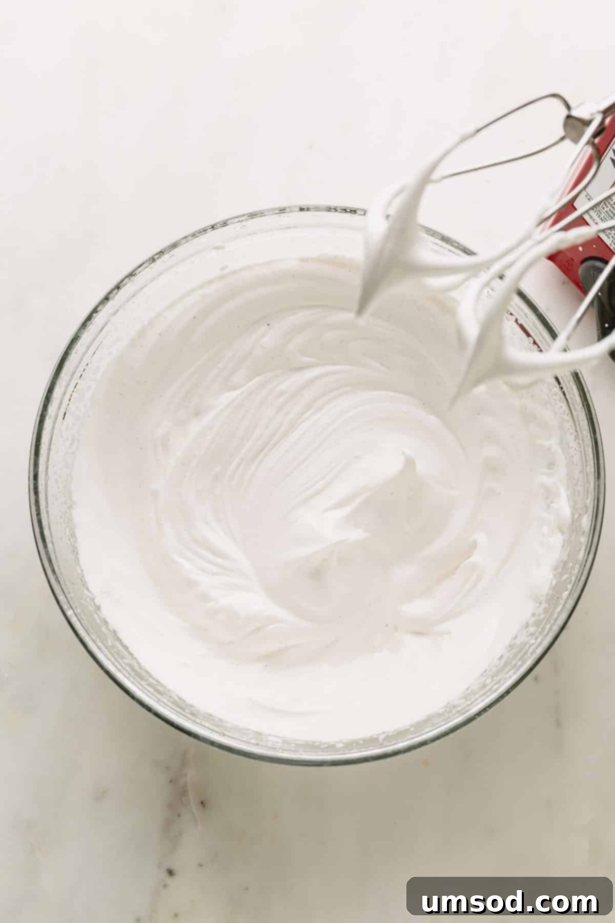 A bowl filled with perfectly whipped, glossy vegan meringue, forming stiff peaks.