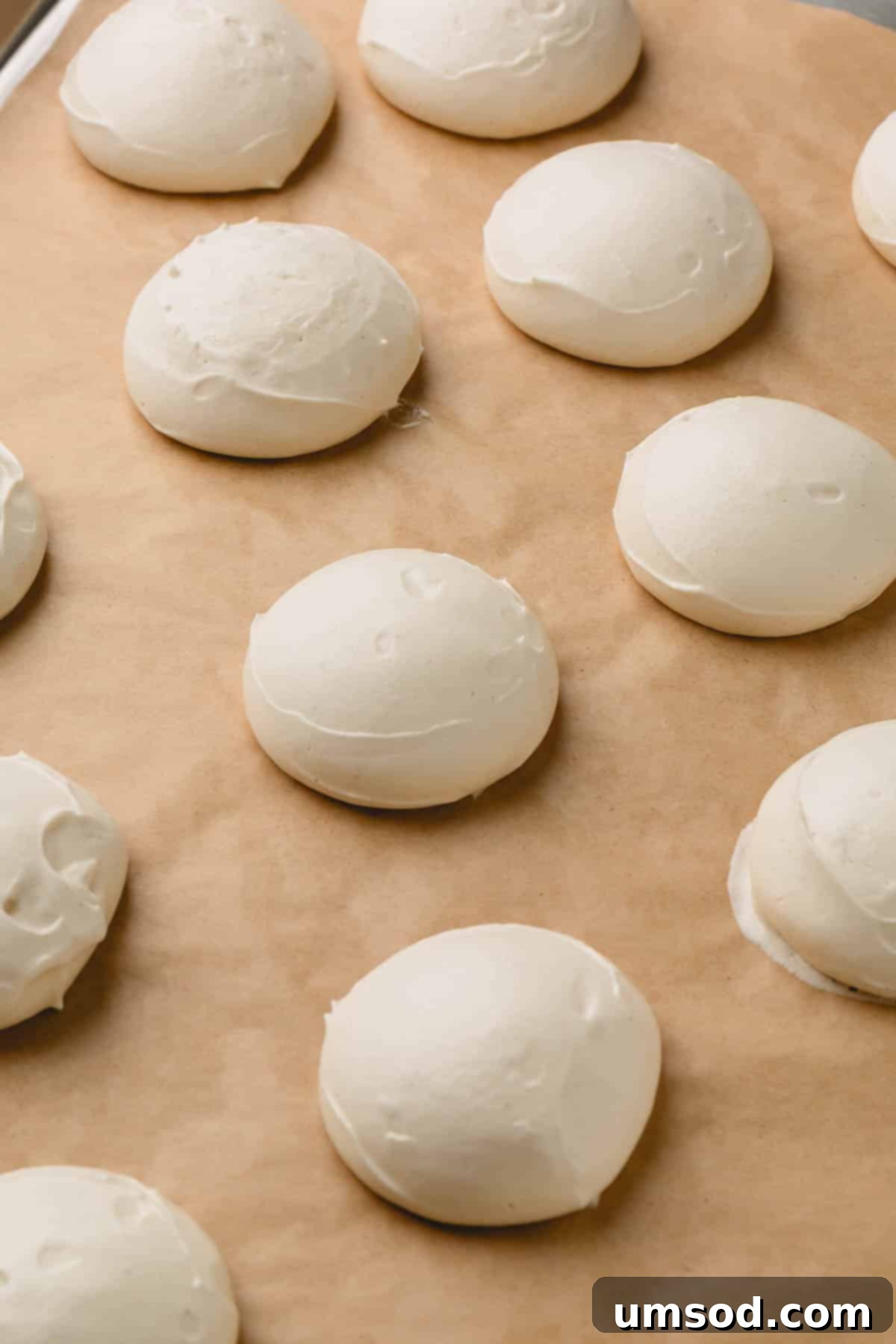 Freshly baked vegan meringue pieces on a parchment paper-lined baking sheet.