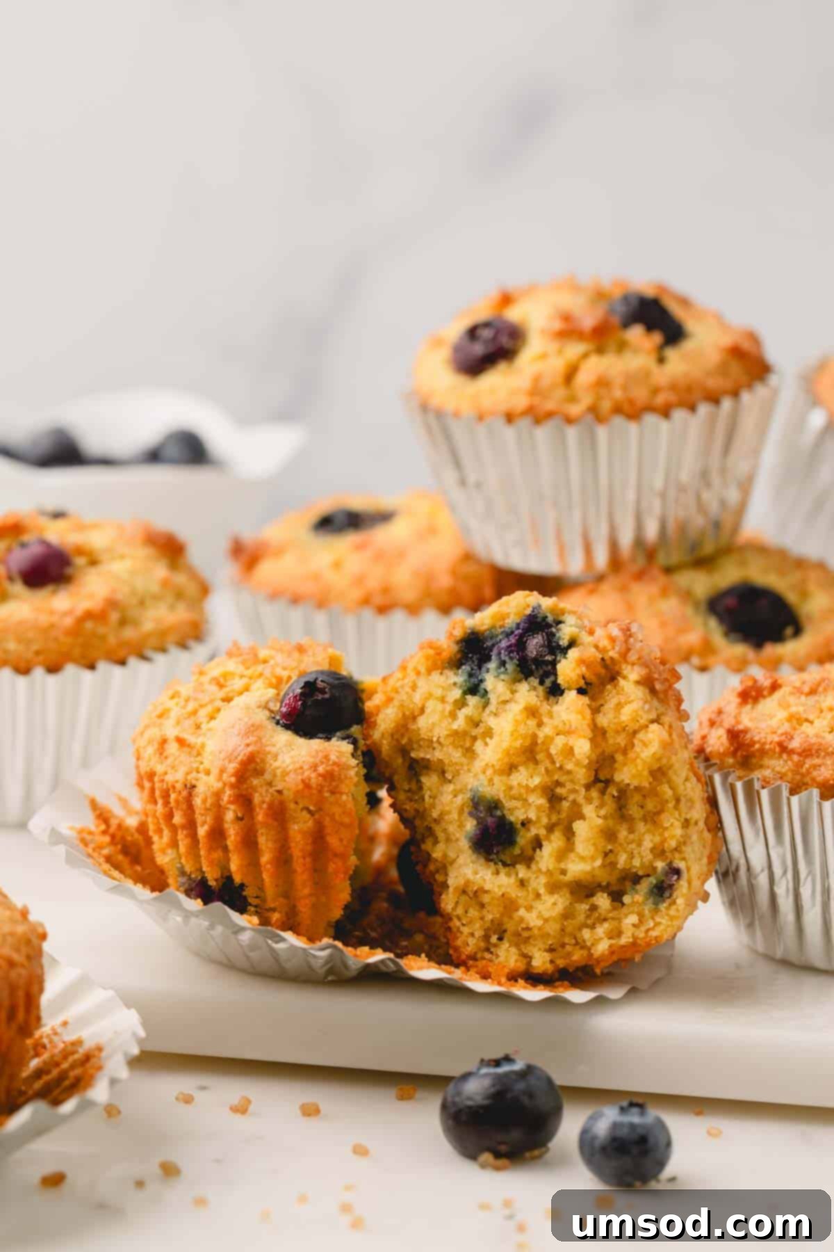 Tender Almond Flour Blueberry Muffins 14 An almond flour blueberry muffin split in half on top of a muffin liner.