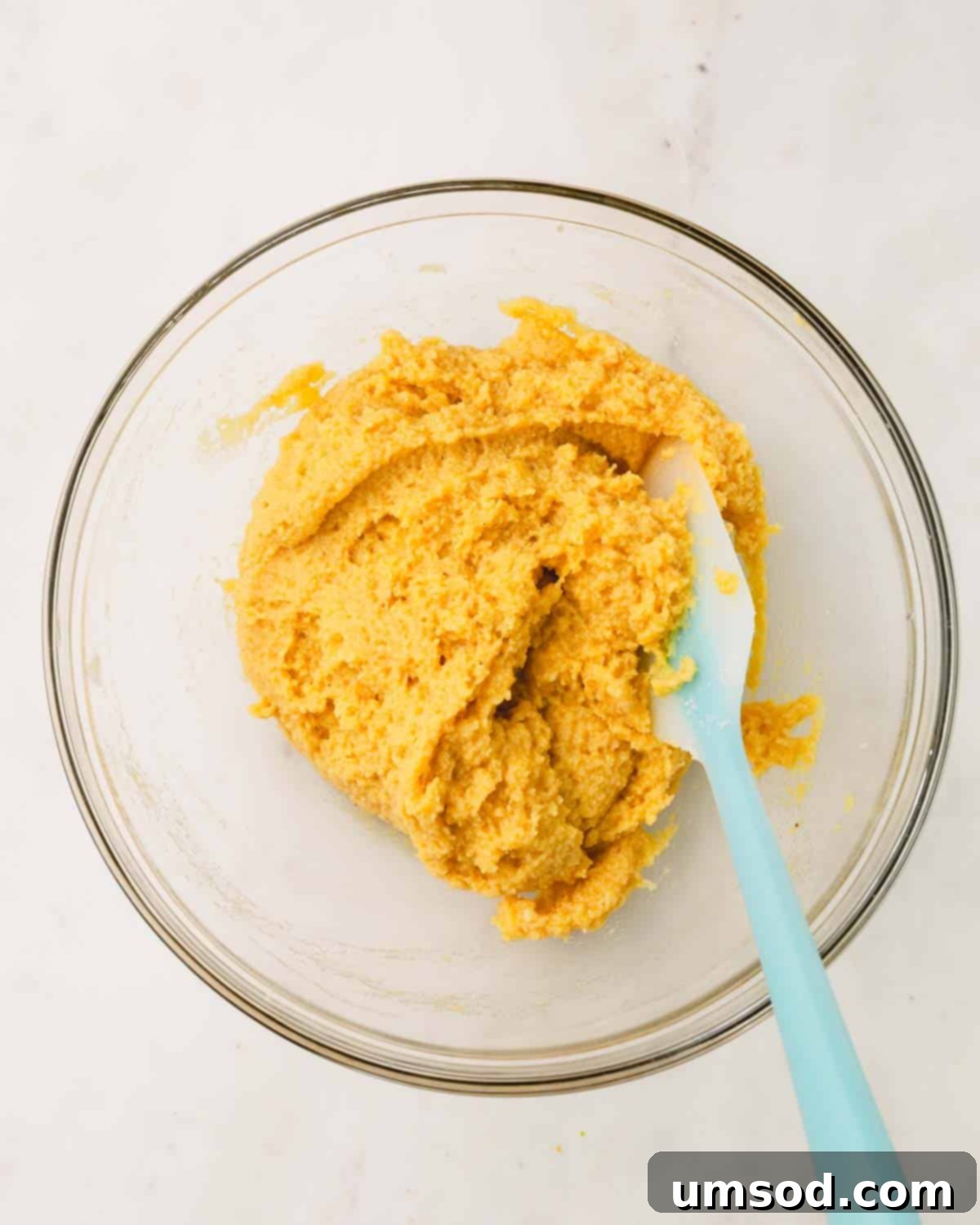 Tender Almond Flour Blueberry Muffins 8 A bowl of almond flour muffin batter with a rubber spatula sticking out.