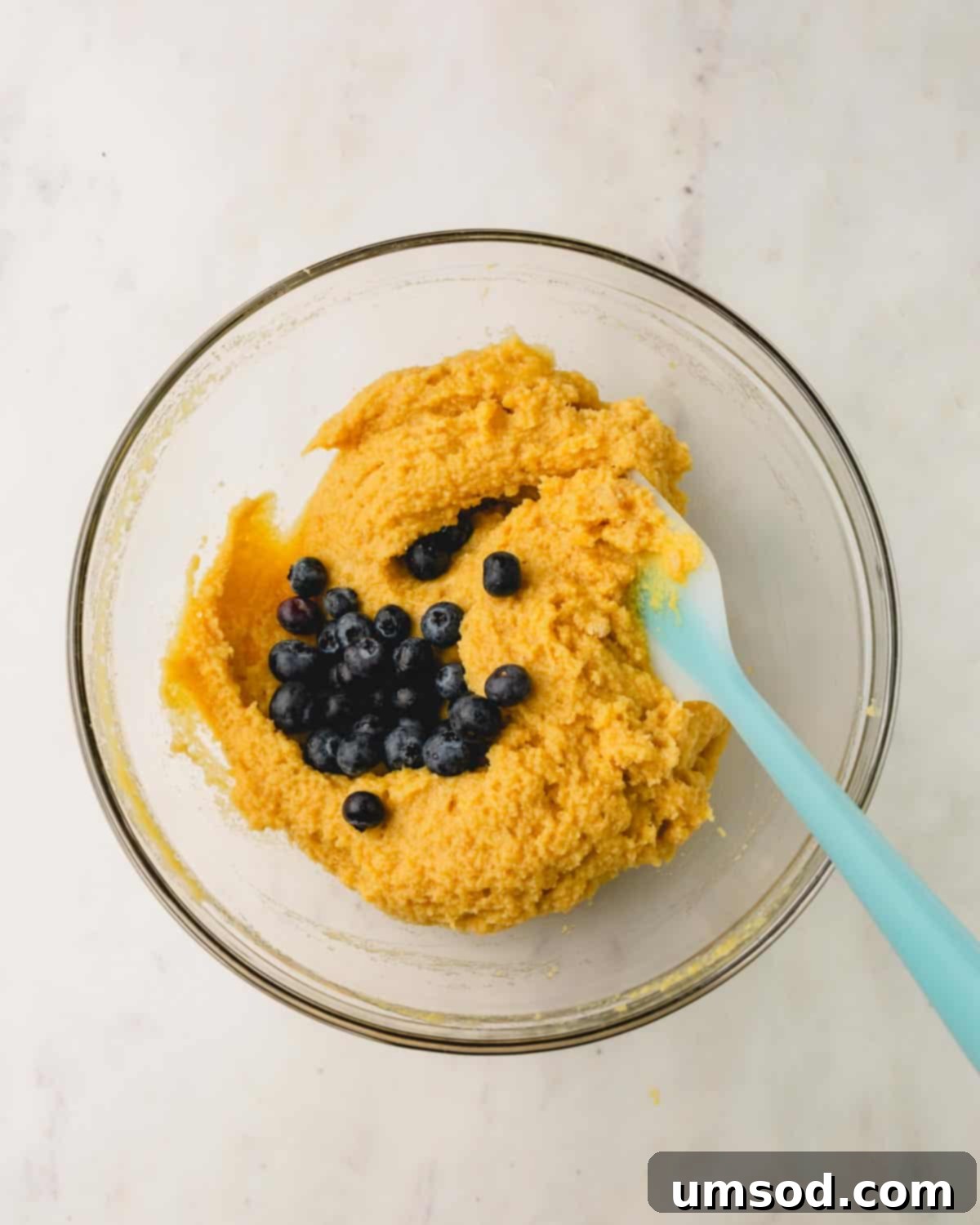 Tender Almond Flour Blueberry Muffins 9 Blueberries being folded into almond flour muffin batter.