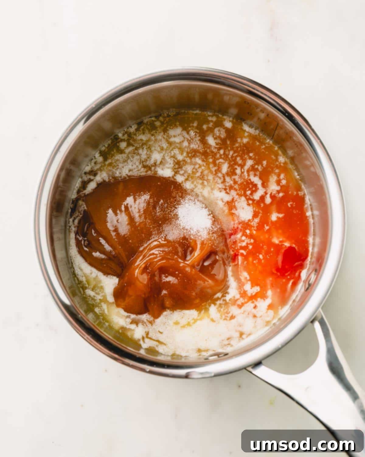 Honey, hot sauce, and salt added to melted butter in a pot, ready to be stirred.