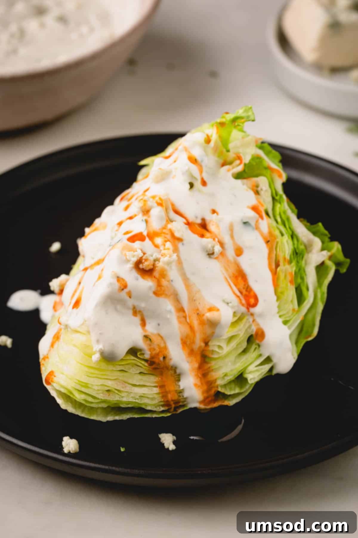 A wedge salad topped with Ranch dressing, a generous drizzle of hot honey sauce, and crumbled blue cheese.