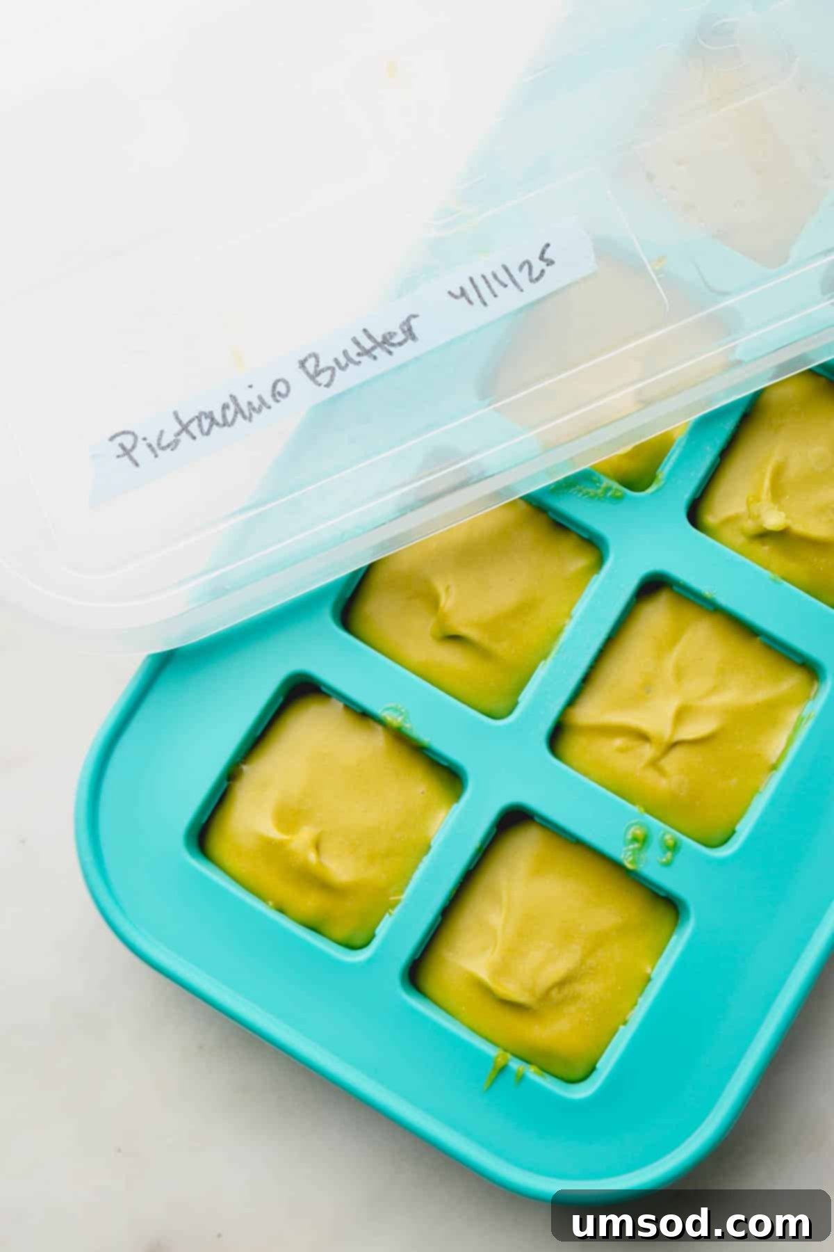 Pistachio butter neatly portioned and frozen in an ice cube tray, ideal for long-term storage.