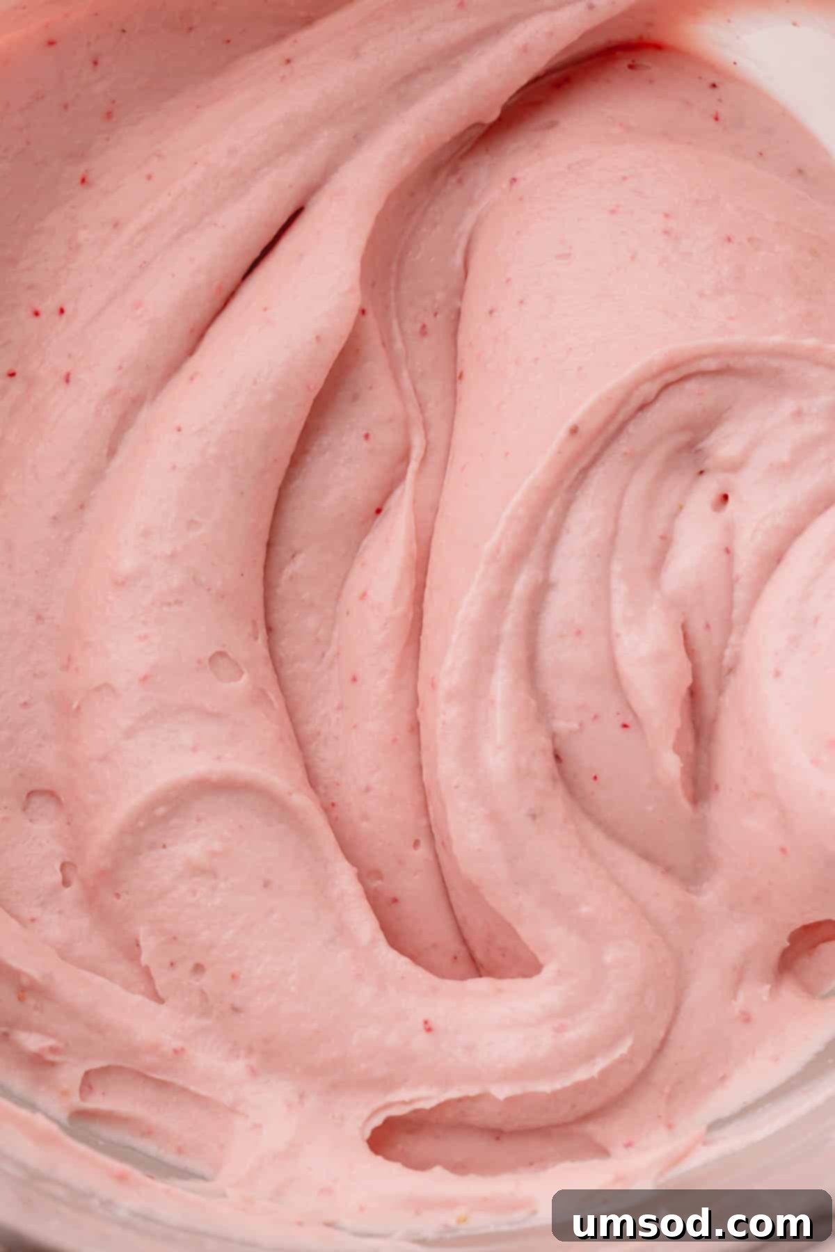 Lush strawberry cream cheese frosting with visible flecks of freeze-dried strawberries, ready to adorn desserts.
