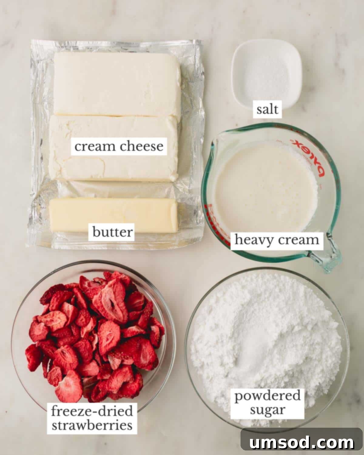 Neatly arranged key ingredients: cream cheese, unsalted butter, freeze-dried strawberries, powdered sugar, heavy cream, and coarse kosher salt.