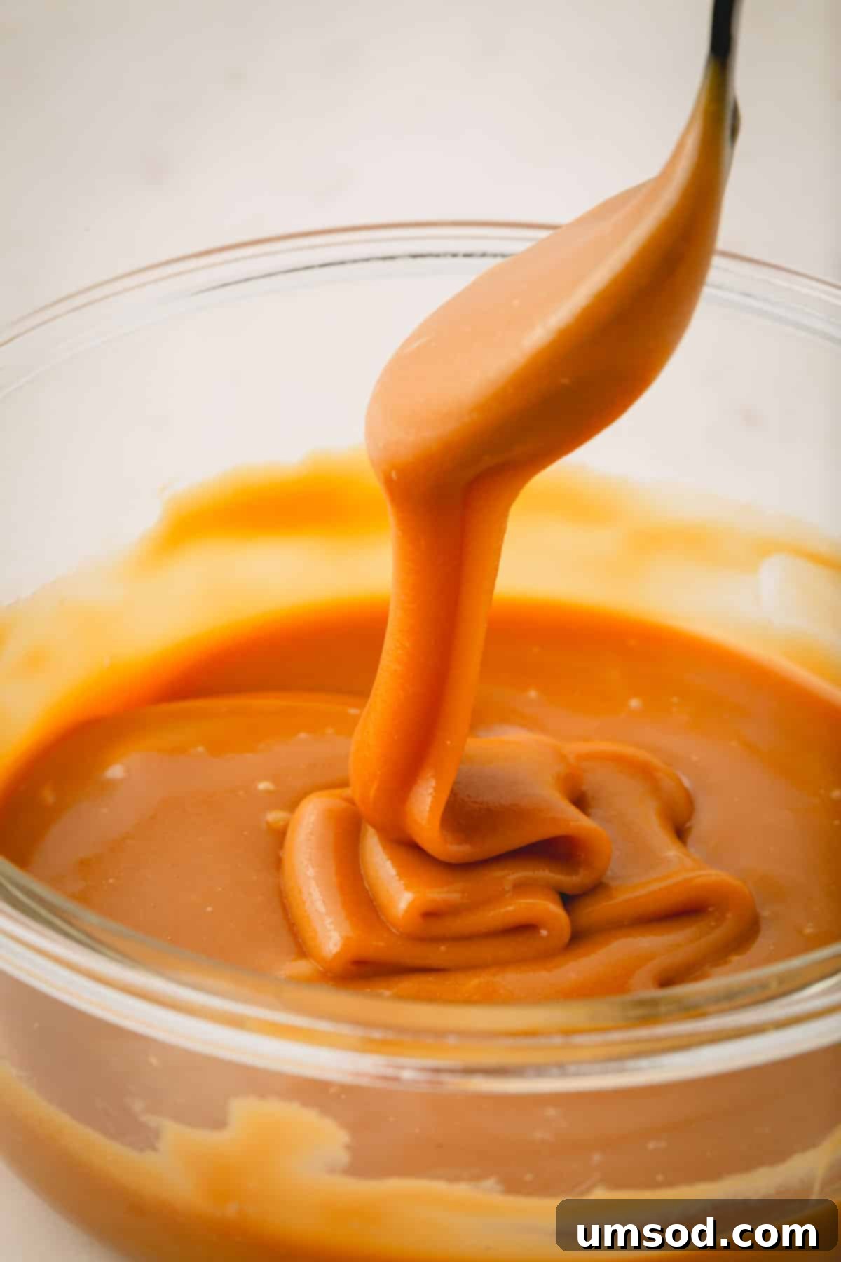 Vegan coconut caramel filling being lifted with a spoon, showing its thick and creamy texture.