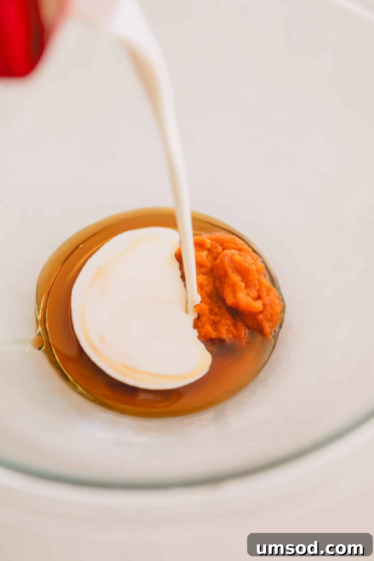 Pumpkin, heavy cream, and maple syrup being combined in a bowl for the frosting.