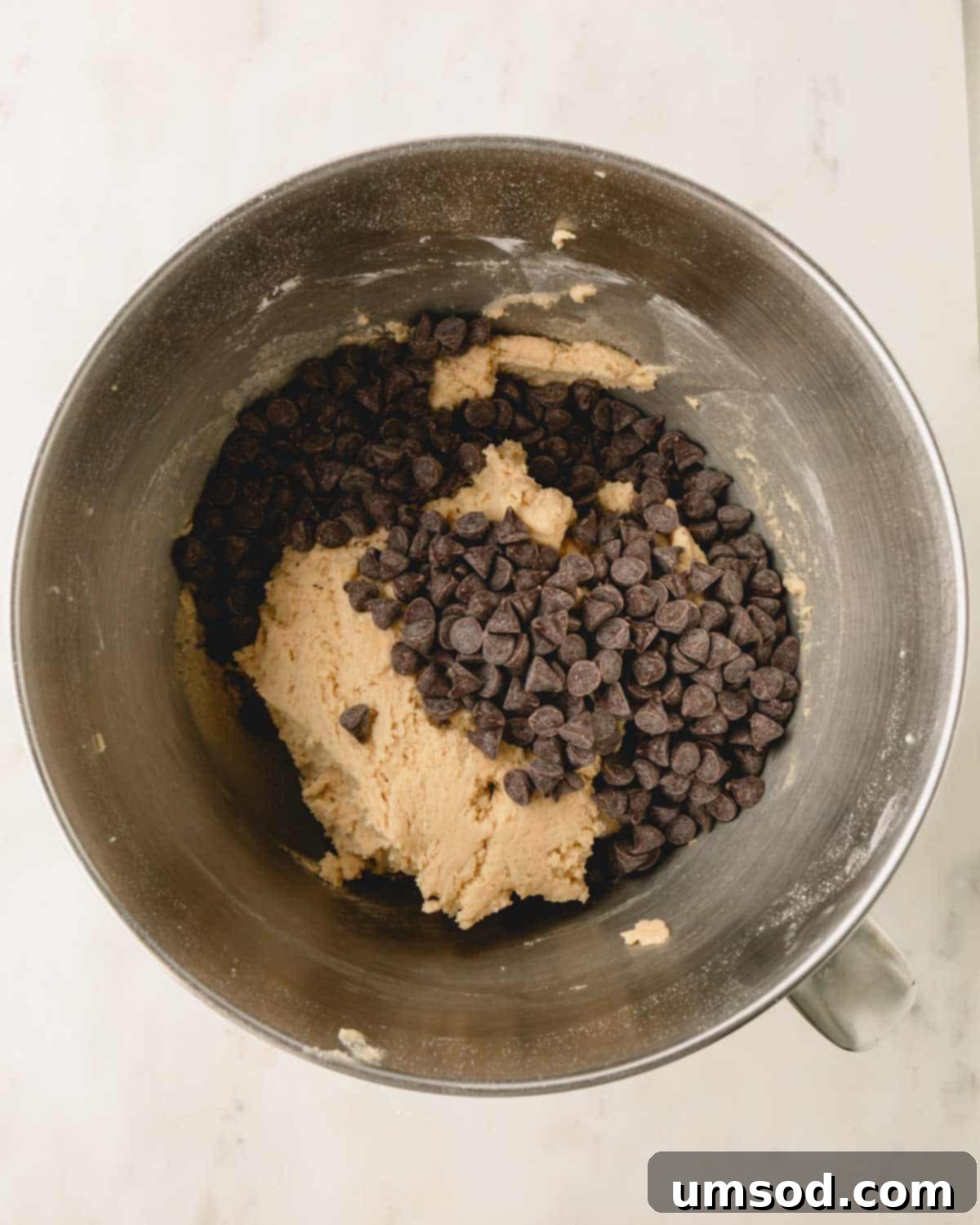 Chocolate chips on top of cookie dough in a bowl.