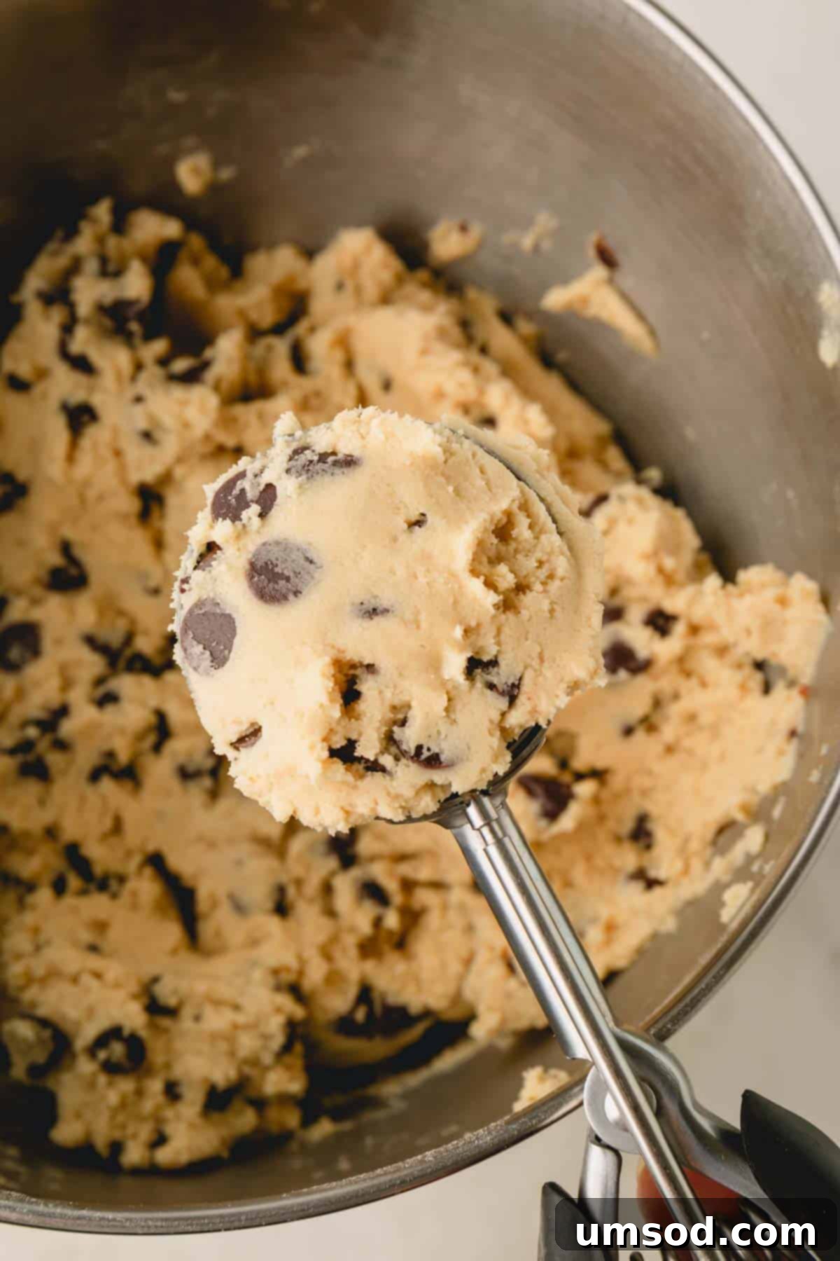 A cookie scoop full of chocolate chip cookie dough.
