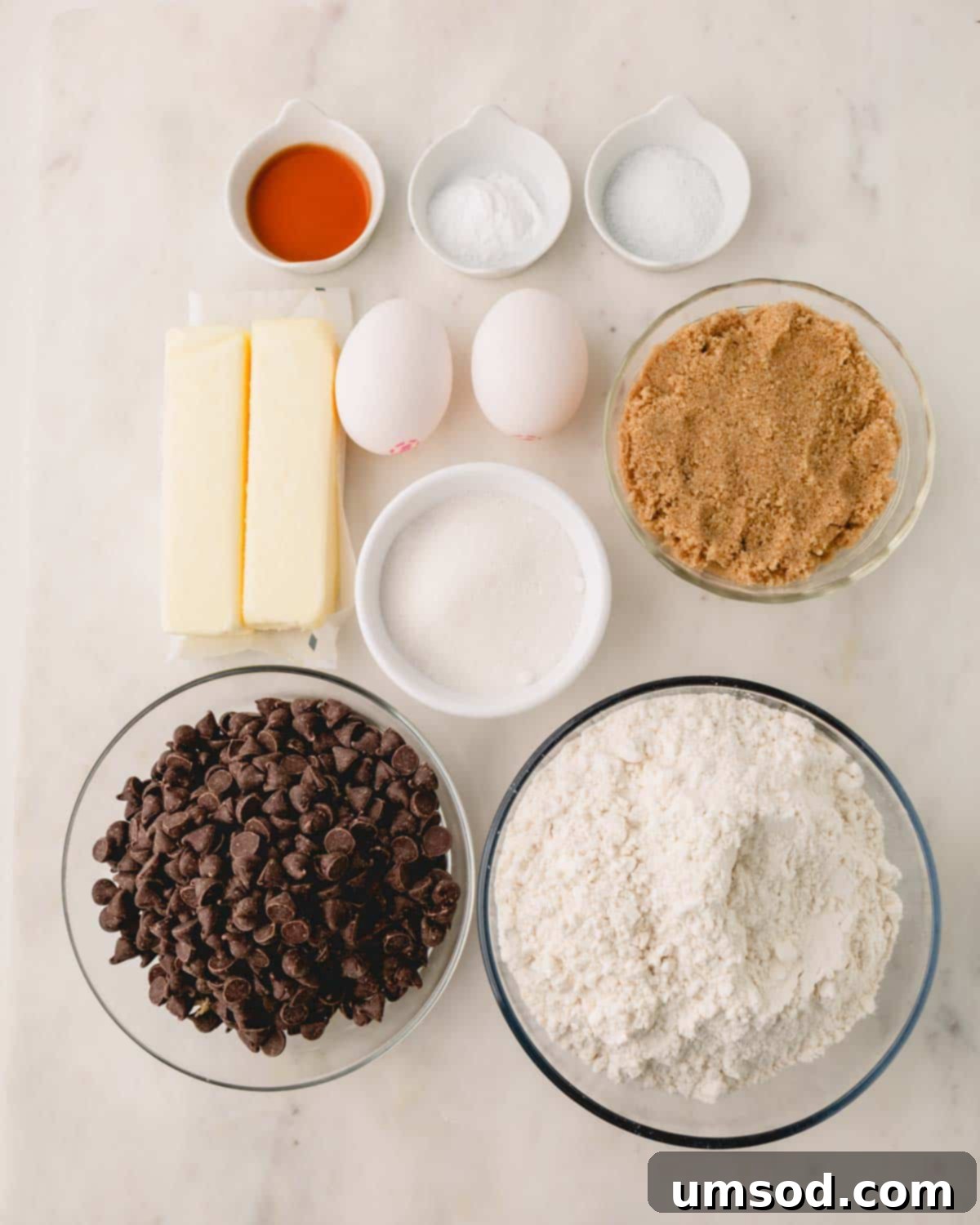 All the essential ingredients for making thick and chewy chocolate chip cookies laid out on a counter.