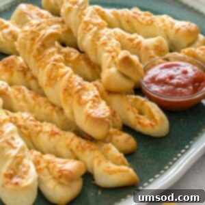 Crispy Garlic Breadsticks 7 Close-up of two perfect roasted garlic and cheese breadsticks on a wooden surface.