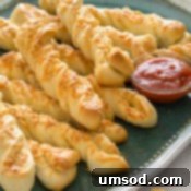 Crispy Garlic Breadsticks 8 Close-up of a single roasted garlic and cheese breadstick, showing its cheesy, twisted texture.