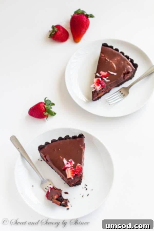Rich chocolate truffle tart featuring a creamy ganache filling and a topping of fresh strawberries and shredded coconut.