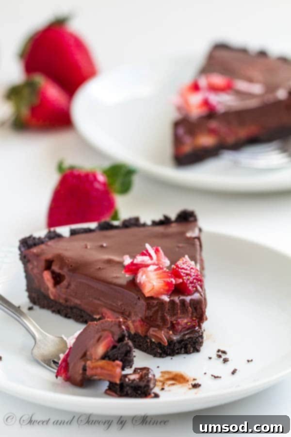 A beautifully presented slice of no-bake chocolate truffle tart, garnished with fresh strawberries and coconut flakes, ready to be enjoyed.