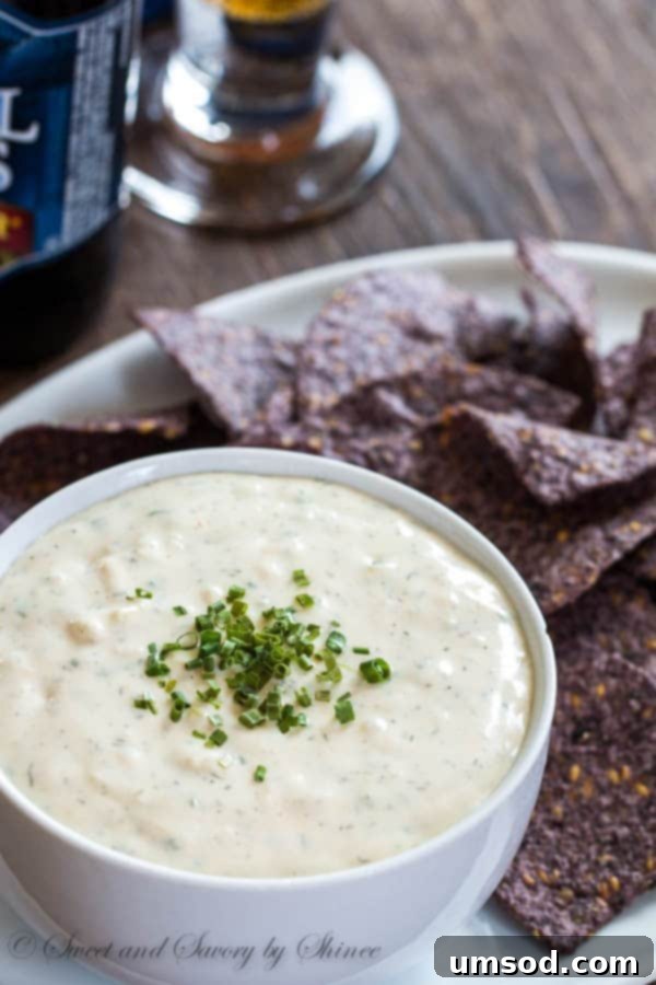 Creamy, golden homemade beer cheese dip served with pretzel bites on a rustic wooden board, ready for a party.