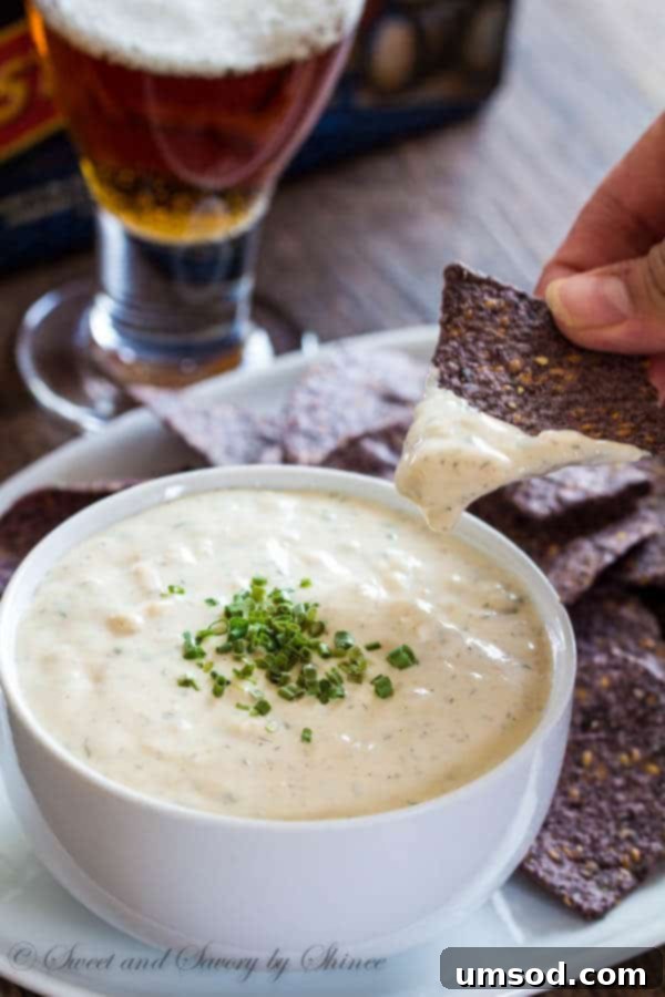 Close-up shot of the rich texture of homemade beer cheese dip in a bowl, with a serving spoon.