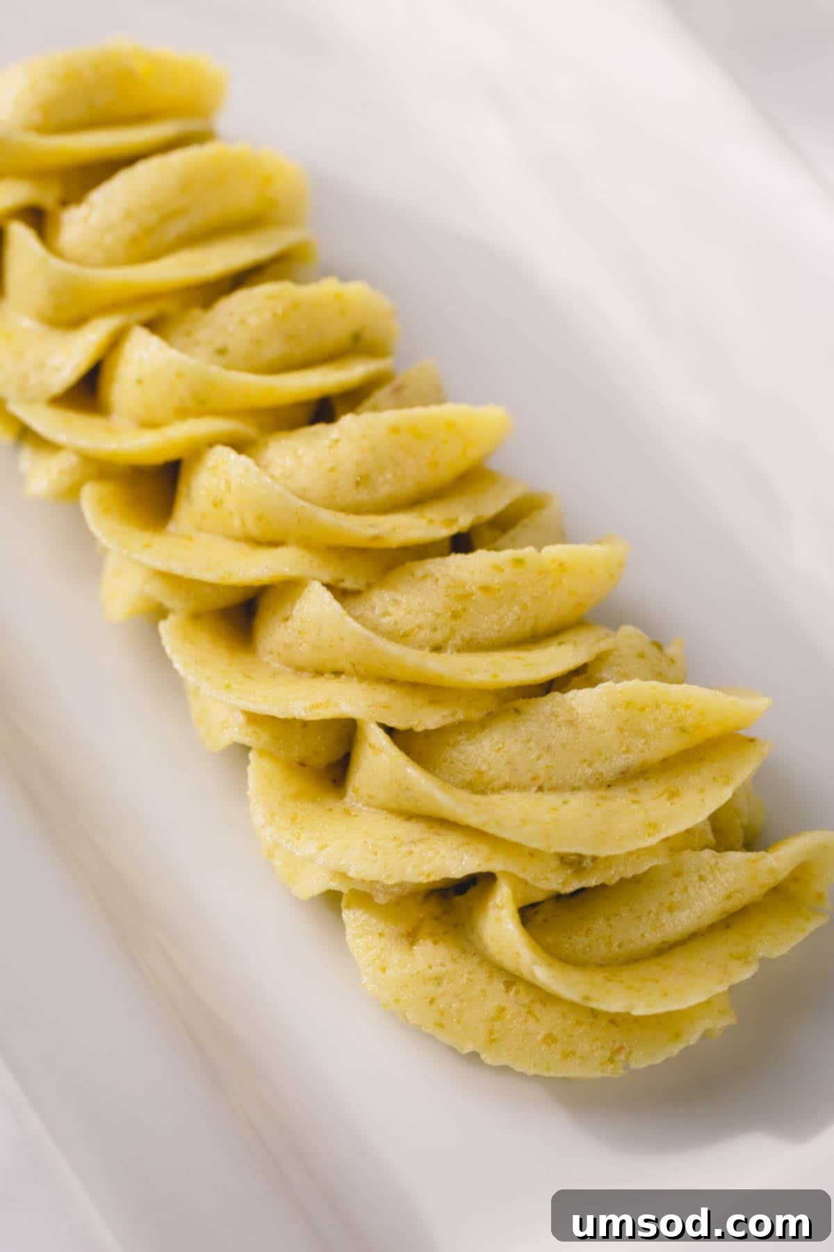 Piped pistachio buttercream on a white plate, showcasing its vibrant natural color and fluffy texture.