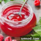 Effortless Pectin-Free Raspberry Jelly 9 A glass jar of raspberry jelly with a spoon dip in it.