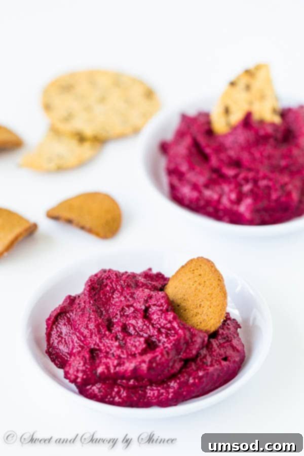 A bowl of vibrant roasted beet dip, garnished with fresh herbs, ready for serving.