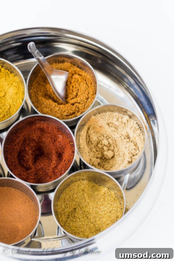 An array of whole and ground spices, including cumin, coriander, and chili powder, ready to be used in a delicious recipe.
