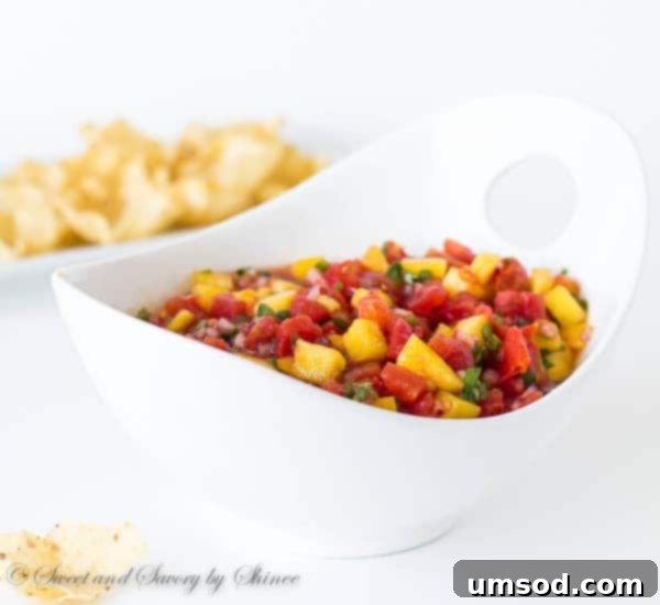 Ingredients for mango salsa including a fresh mango, diced tomatoes, onion, and cilantro