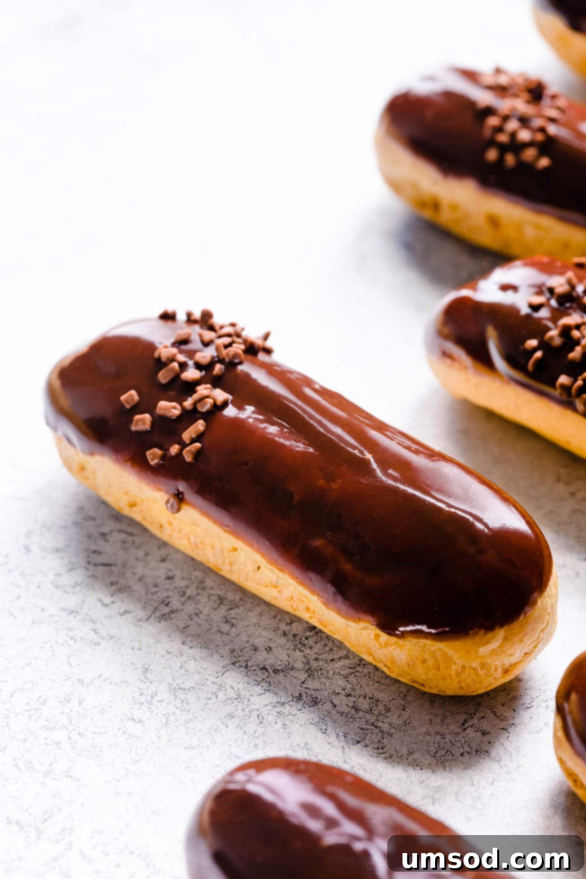 Decadent Chocolate Eclairs 2 Upclose shot of chocolate eclair, showcasing its perfect golden shell, creamy filling, and shiny chocolate glaze.