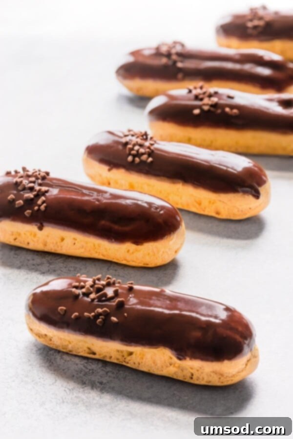 Decadent Chocolate Eclairs 3 Collection of freshly baked chocolate eclairs arranged neatly on a counter.