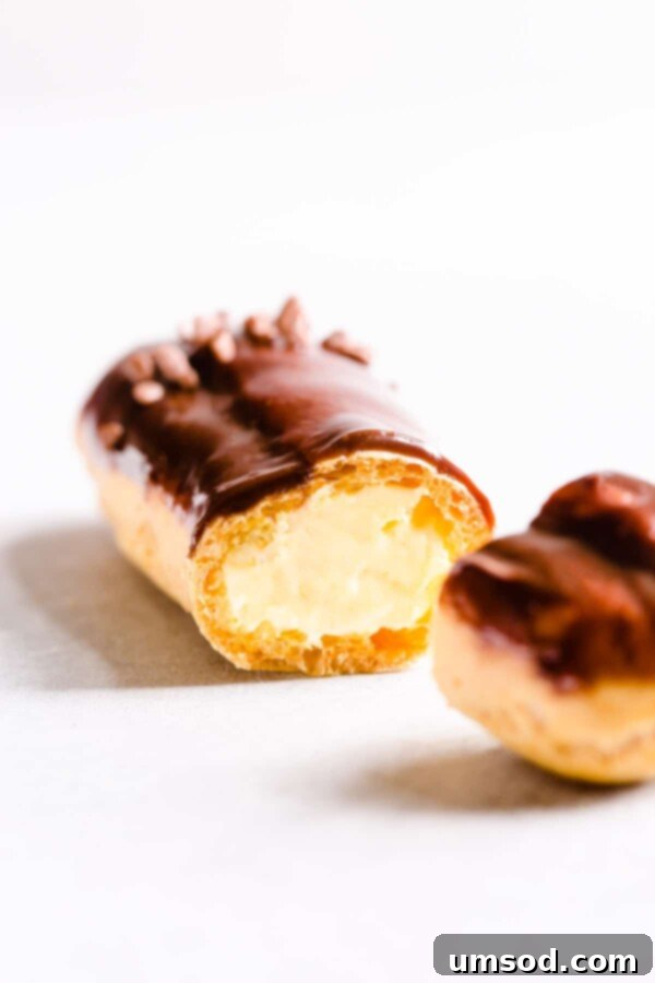 Decadent Chocolate Eclairs 4 Detailed shot of a sliced chocolate eclair, revealing its perfectly golden shell and creamy pastry cream filling.