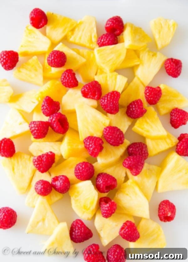 Close-up of Pineapple Raspberry Sangria poured into a glass, garnished with fresh fruit and mint