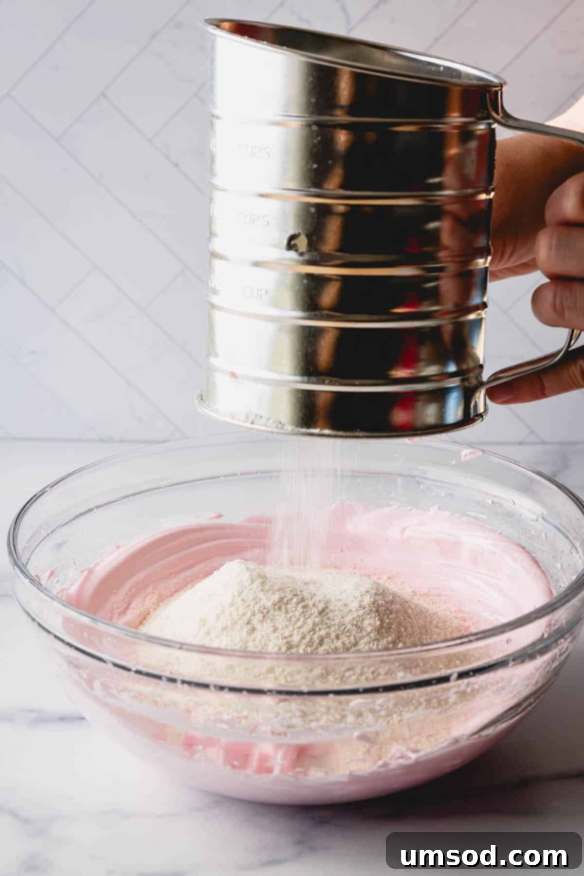 Foolproof Macarons for First-Timers 11 Dry ingredients being sifted into the pink meringue.