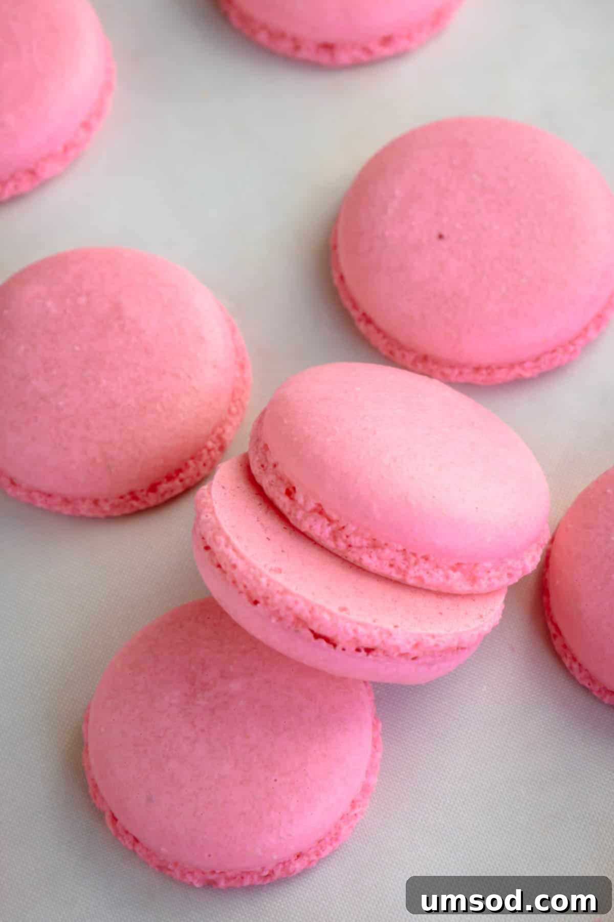Foolproof Macarons for First-Timers 17 Pink macaron shells on a white surface.