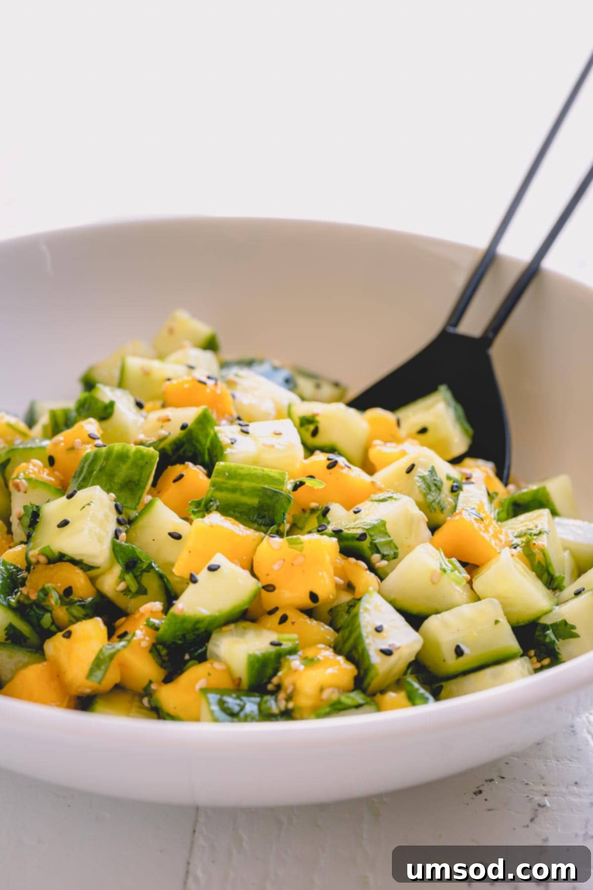 Cucumber mango salad in a white salad bowl, ready to be served.