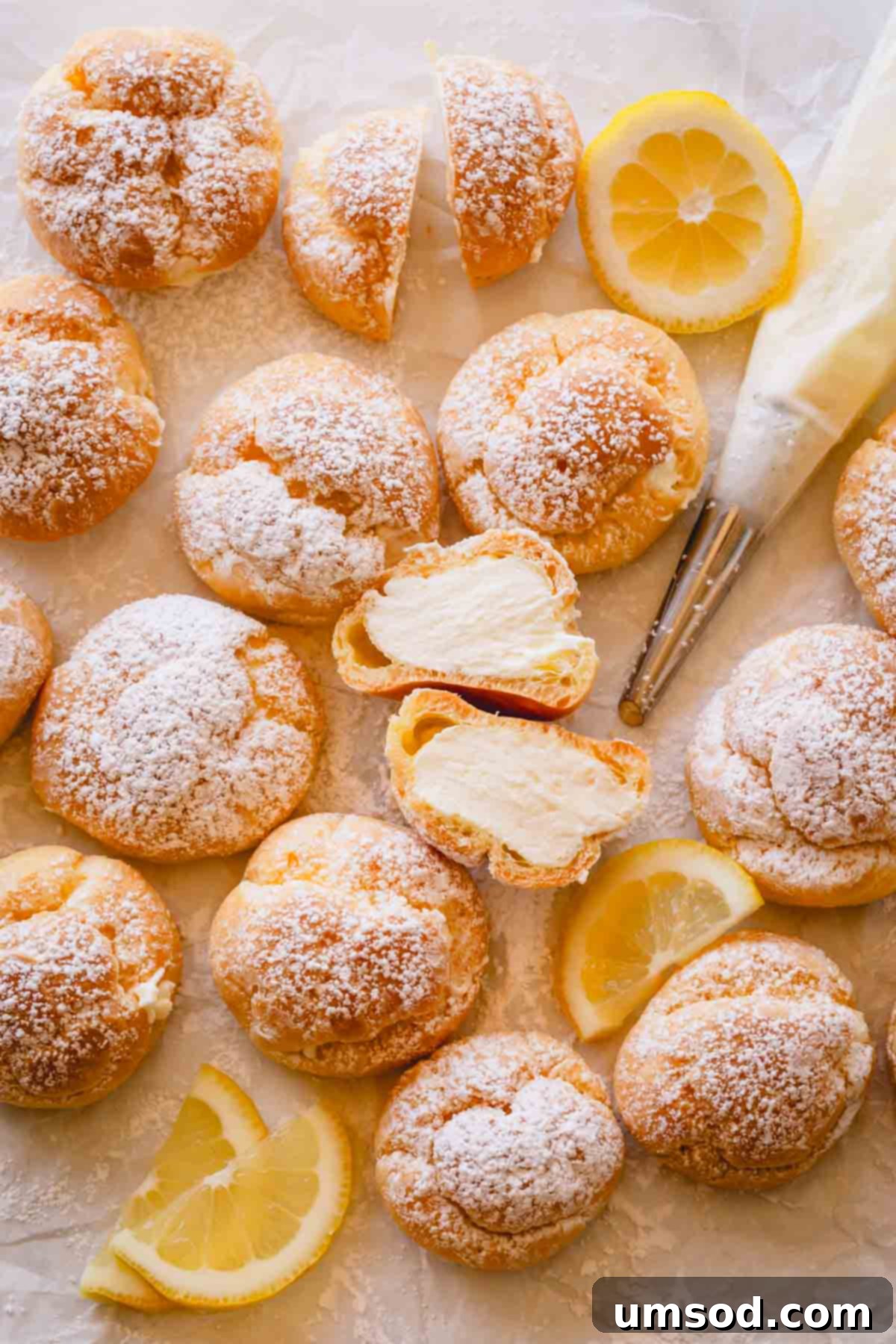 Zesty Lemon Cloud Puffs 3 Lemon creme puffs with one split in half, revealing the bright, creamy lemon curd filling.
