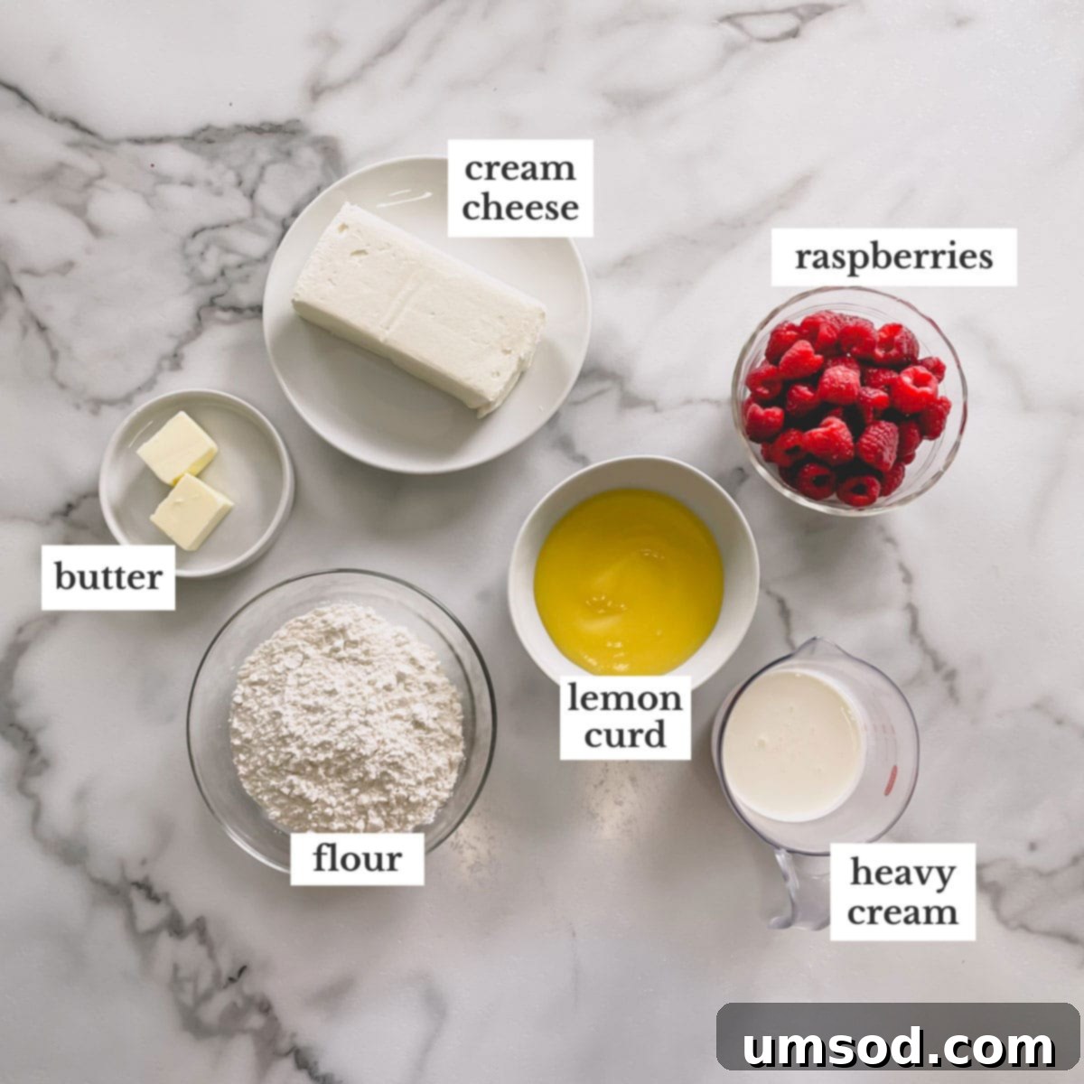 Zesty Raspberry Lemon Mini Tarts 3 Key ingredients for making lemon raspberry tartlets, including cream cheese, butter, flour, heavy cream, lemon curd, and fresh raspberries, laid out on a clean surface.