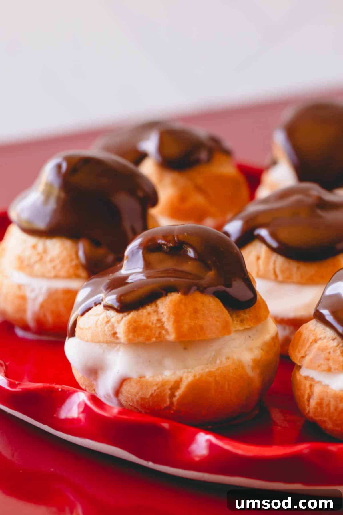 A delectable stack of chocolate profiteroles presented elegantly on a white plate, garnished for serving.