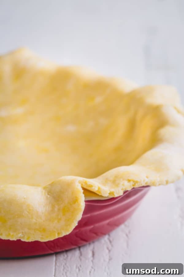 A freshly rolled out pie dough carefully draped over a deep pie dish, showcasing its readiness for crimping.