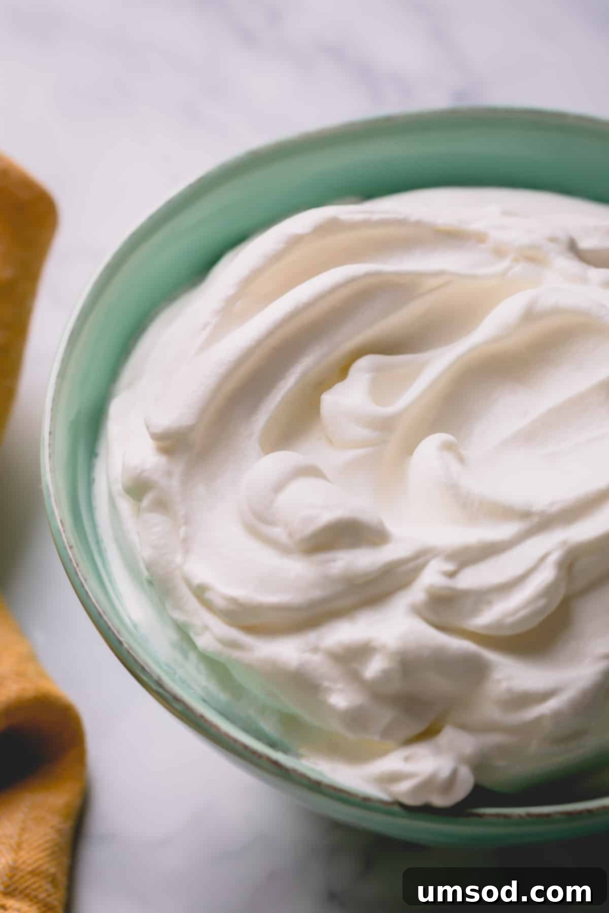 A beautiful bowl of creamy, fluffy homemade whipped cream, ready to be served.