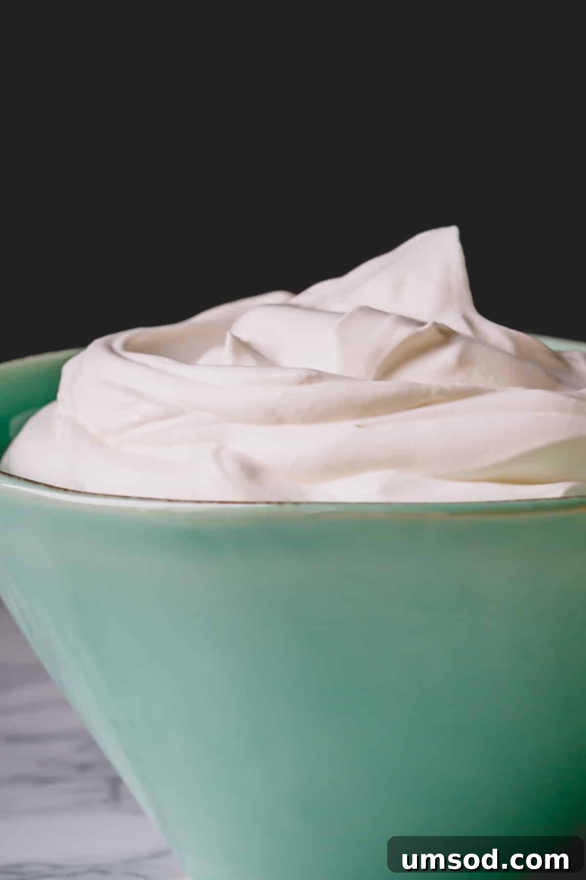 A large serving bowl filled with an abundance of perfectly whipped, airy, and tangy homemade yogurt whipped cream, ready for any occasion.