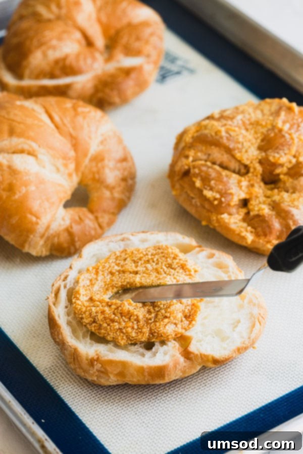 Spreading pumpkin filling generously inside and on top of sliced croissants before baking. This creates a crispy, delicious crust. #pumpkineverything #pumpkindessert #pumpkincroissant