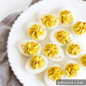 Golden Curry Deviled Eggs 6 A top-down view of a plate of Curry Deviled Eggs with a golden, creamy filling and sprinkled with paprika.