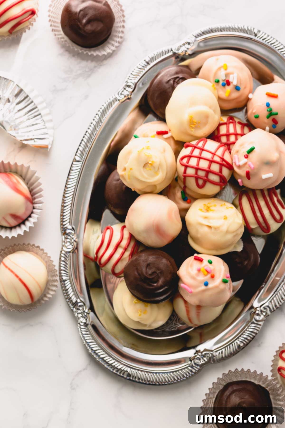 A vibrant assortment of colorful Oreo balls artfully arranged on a gleaming silver serving platter.