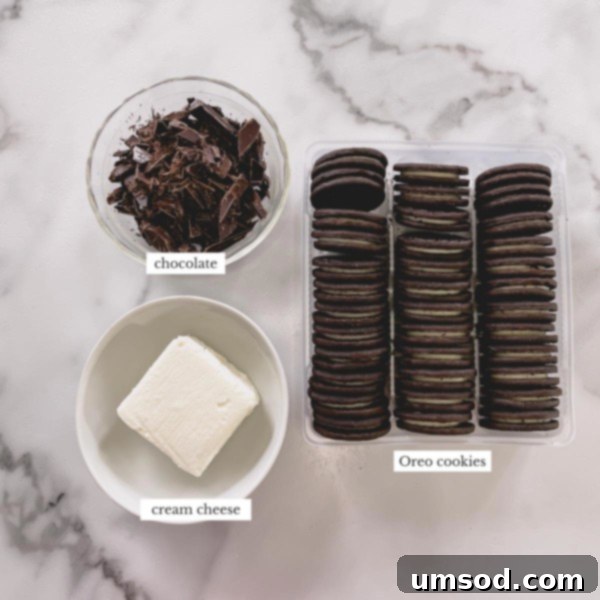 A clear photo displaying the three essential ingredients for classic Oreo balls: Oreo cookies, cream cheese, and chocolate.