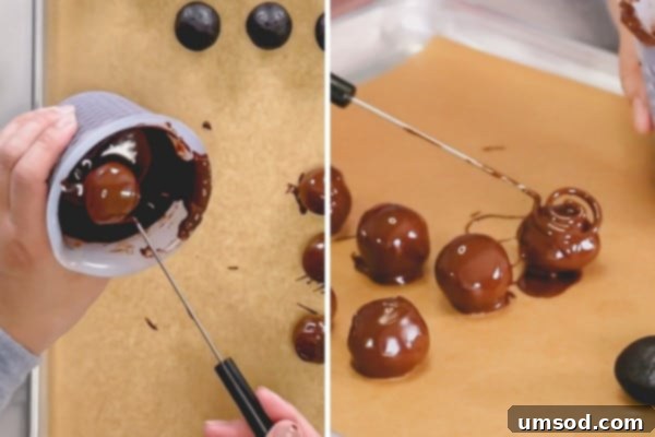 An Oreo ball being perfectly coated in chocolate using a specialized candy dipping tool, ensuring an even layer.